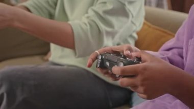 Neşeli Afro-Amerikan ergen kız ve modern annesinin evlerinde birlikte vakit geçirdikleri kontrolörlerle konsolda oyun oynamalarının orta boy yakın çekimi.