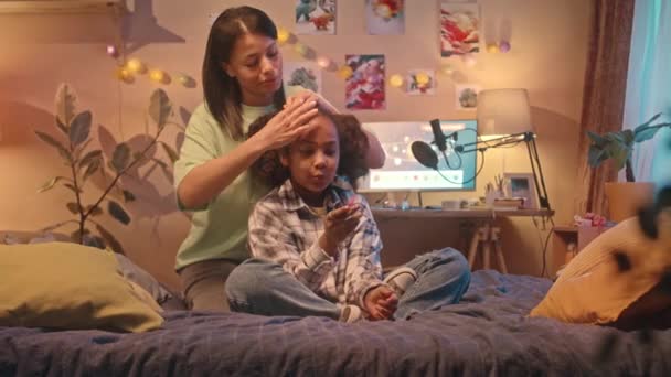 Cuidar Jovens Biracial Mãe Fazendo Filhas Cabelo Enquanto Sentado Cama — Vídeo de Stock