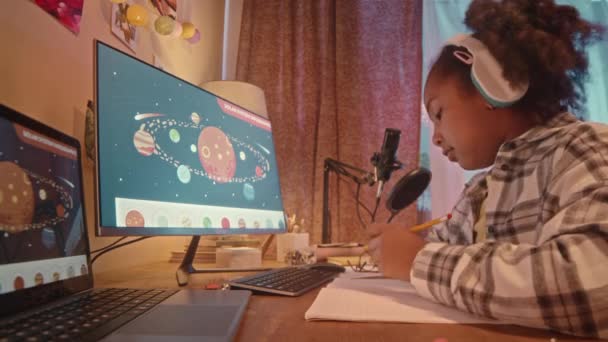 벽지에 태양계의 행성과 컴퓨터에 책상에 앉아있는 헤드폰과 그림에서 음악을 아프리카계 — 비디오