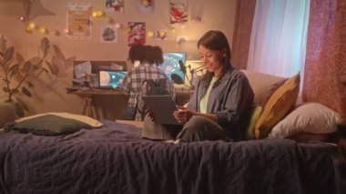 Modern çift ırklı anne gece geç saatlerde kızlarının odasında oturup bilgisayarında görüntülü konuşma yapıyor.