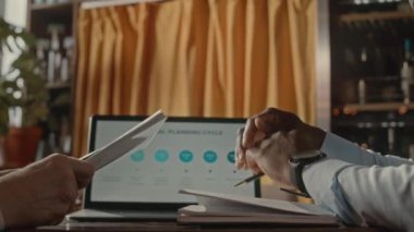 Tanımlanamayan çeşitli erkek girişimcilerin, üzerinde iş slaytı sunumu olan dizüstü bilgisayara karşı el sıkışmaları, restoranda başarılı bir anlaşma yapmaları.