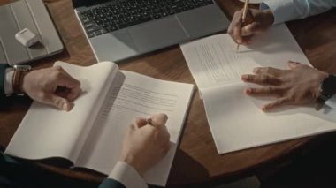 Tanımlanamayan iki başarılı iş adamının sözleşme imzalayıp el sıkışarak kapalı alanda anlaşma yapmalarının yukarıdan çekimleri.