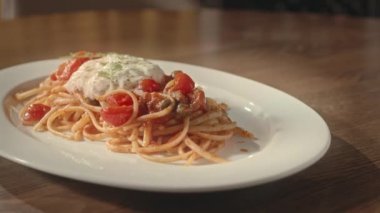 Çağdaş restoran masasında vişneli domatesli spagetti, stracciatella ve pesto.
