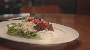 Sosyetik restoranda akşam yemeği için tabakta marul ve beyaz soslu lezzetli orta boy biftek.