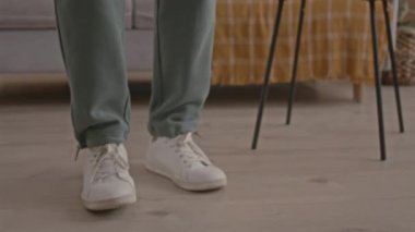 Gündüz vakti oturma odasında dans eden, kablosuz kulaklıklı, zinde bir zenci.