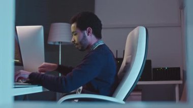 Orta Doğu erkek sistem yöneticisi programının karanlık ofisteki masaüstü bilgisayarında orta görünümü