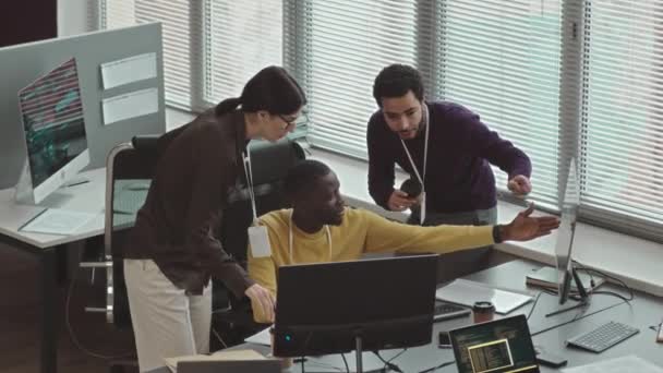 現代のオフィスでソフトウェア開発を議論する多種多様なプログラマのグループの上記ショットから — ストック動画