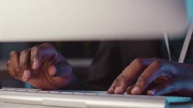 Karanlık sunucu odasındaki kablosuz klavyede yazan hacker 'ın tanımlanamayan siyah erkek ellerine yakın çekim