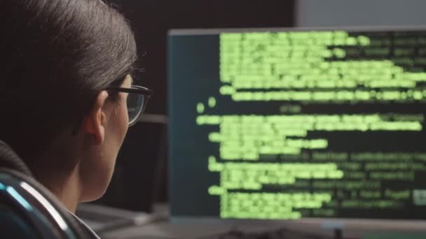 ダークオフィスのデスクトップコンピュータに座っている女性プログラマーのバックビュー 洗練されたプログラムコード — ストック動画