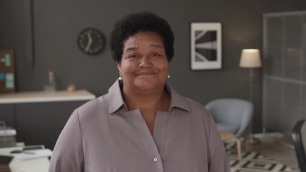 一个快乐成熟的卷曲黑人女人的蜡像 她看着站在现代石墨墙办公室里的相机 — 图库视频影像