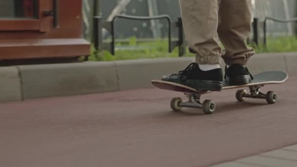 歩道でスケートボードに乗っているスニーカーの認識できない男の子の低いセクション — ストック動画