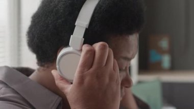 Kablosuz kulaklık takan, ofis işleri arasındaki rahatlatıcı müziğin keyfini çıkaran yaşlı Afrikalı Amerikalı kadının yakın çekimi.