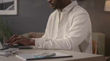 Ofisteki dizüstü bilgisayarda çalışan Afrikalı Amerikalı iş adamının orta boy fotoğrafı.