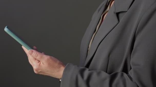 用灰色背景智能手机拍摄的无法辨认的中年妇女穿着正式夹克的剪影 — 图库视频影像