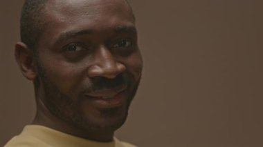 Stüdyonun arka planında kamerayla flört ederken kaşını kaldıran yakışıklı zenci portresi.