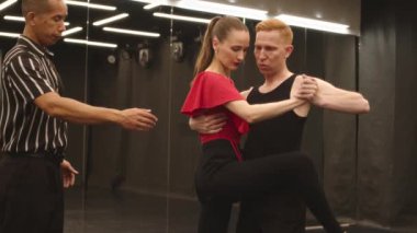 Çift ırklı erkek öğretmenle dans kursuna katılırken dans etmeyi öğrenen genç, beyaz bir kadın ve partneri onlara ritim ve vücut dili konusunda yardımcı oluyor.