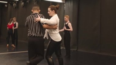 Geniş ve modern dans sınıfında tango yapan çok ırklı genç bir çift.