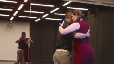 Geniş stüdyoda ışıkla dans eden çok ırklı genç ve şehvetli çift balo salonu.