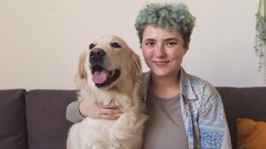 Yapay kollu, gülümseyen beyaz bir kızın yavaş portresi ve sevimli labrador Retriever 'ı kanepede oturup kameraya bakıyor.