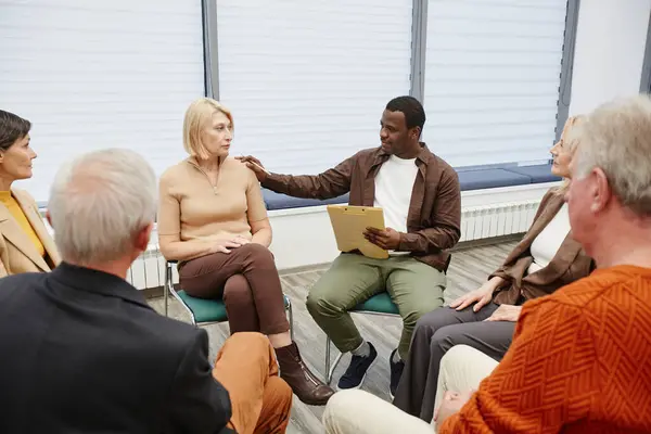Group of people sitting in circle and talking to each other during psychological therapy at class