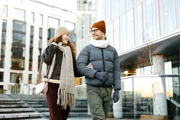 暖かい服を着た若者は 仕事の後に通りを歩いている間にガールフレンドに話しかけます — ストック写真