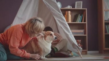 6 yaşında, Down sendromlu beyaz bir çocuk, annesiyle çocuk çadırında oynuyor ve tatlı köpekleri evde vakit geçiriyor.