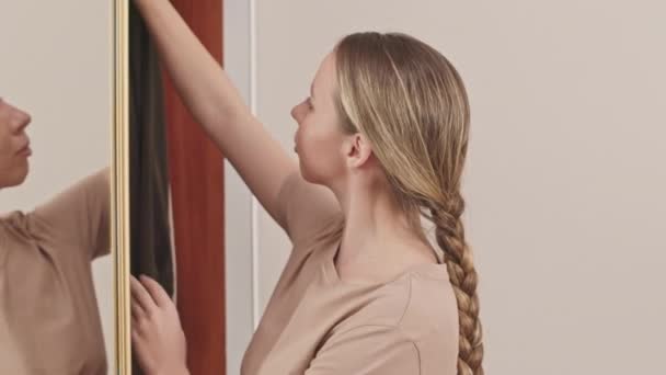 照片中站在卧室衣柜边的白人年轻女子选择穿什么 试穿镜前衣架上的衣服 — 图库视频影像