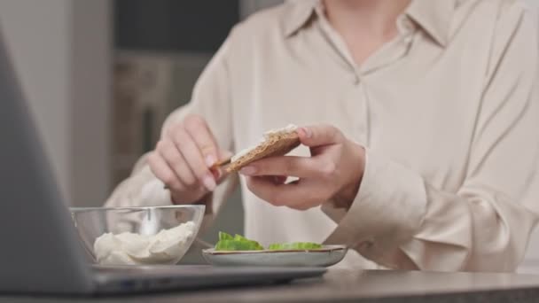 認識できない女性のクリームチーズをスパイスブレッドの上に広げ 週末に自宅で朝食を食べながらキュウリのスライスを上に置く — ストック動画