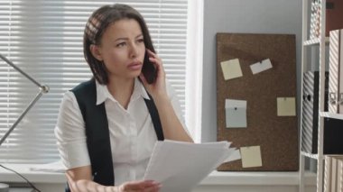 Modern ofisteki erkek arkadaşlarıyla telefon görüşmesi yapan iki ırklı genç bir kadın güvenlik görevlisi.