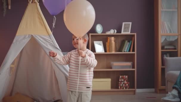 Tiro Médio Criança Feliz Com Síndrome Jogando Balões Festa Coloridos — Vídeo de Stock