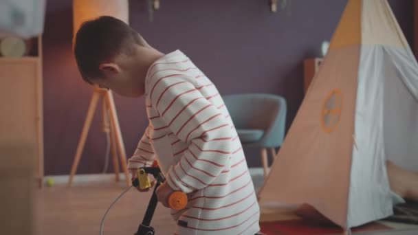 Liten Pojke Med Ner Syndrom Försöker Cykla Rymliga Vardagsrum — Stockvideo