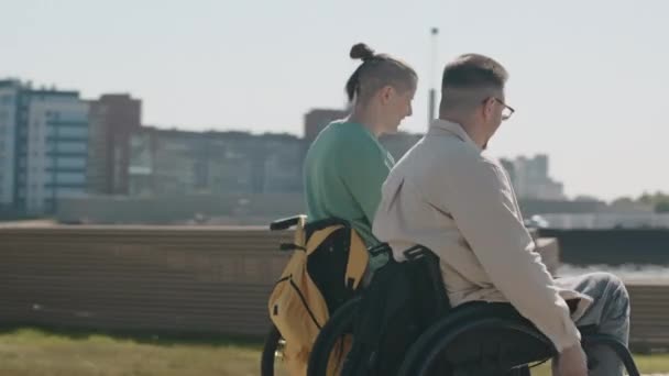 Śledzenie Ujęcia Dwóch Wesołych Białych Przyjaciół Ścigających Się Wózkach Inwalidzkich — Wideo stockowe