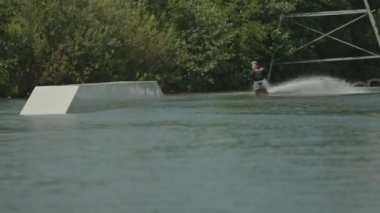 Bacakları olmayan neşeli Kafkas genci. Uyumlu yelkenlide oturuyor ve nehirde halatla çekilerek sörf yapıyor.