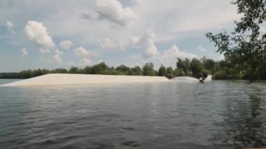 Bacakları olmayan genç sörfçü yazın açık havada halatla sörf yapıyor.