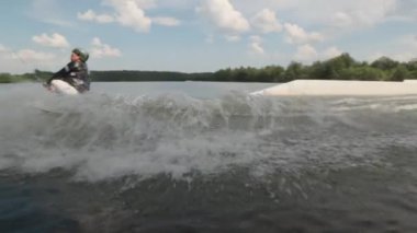 Yazın nehirde bacakları olmayan, halat tutan ve tekneyle çekilen donanımlı genç bir çocuk.