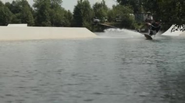 Engelli genç sörfçü güneşli bir günde nehirde sörf yaparken uyanma tahtası ve ipi kullanıyor.