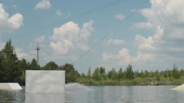 Kafkasyalı engelli genç sörfçülerin yavaşı halat tutarken kaydırağın üzerinden suyun içinde açık havada atlıyor.