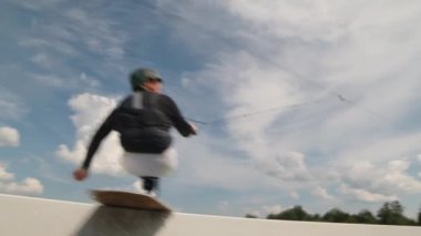 Bedensel engelli sörfçü yaz aylarında açık havada uysal wakeboard eğitimi alırken sürgülü sürgüde numaralar yapıyor.