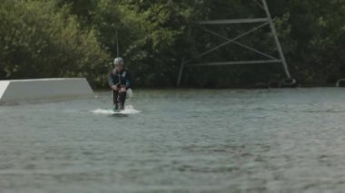 Engelli genç atletizm sporcusu yaz mevsiminde nehirde sörf yapmaya çalışırken güvenlik kaskı ve dalış kıyafeti giyiyor.