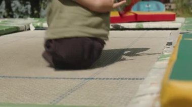 Bacakları olmayan, yaz günü trambolinde zıplayarak eğlenen Kafkas ergen bir çocuk.