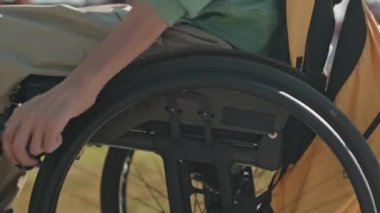 Engelli bir adamın, yaz şehri boyunca tekerlekli sandalyeyle dolaşırken çekilmiş görüntüsü.