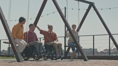 İki genç kadın salıncakta sallanırken yaz gezintisinde iki tekerlekli sandalyeli adamla buluşuyor, sohbet ederek iyi vakit geçiriyorlar.