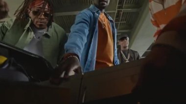 Üç Afrikalı Amerikalı ve beyaz arkadaşları arabanın bagajından müzik setini indirip otoparkta hip hop müzik dinliyorlardı.