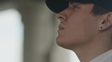 Kulağında küpe, şapkasında ot tüttüren Kafkasyalı kötü çocuğun orta boy yakın çekimi.