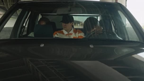 通过挡风玻璃拍摄的三个非裔美国年轻人和他们的白人伴侣坐在黑色汽车上 听嘻哈音乐 — 图库视频影像