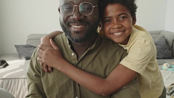 把一个快乐的非裔美国人的画像挂起来 他和十几岁的儿子肩头抱着他 对着相机笑着 白天呆在家里 — 图库视频影像