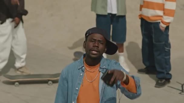 スケートパークの屋外で積極的にカメラで行動する彼のギャングと積極的な黒人男性 — ストック動画
