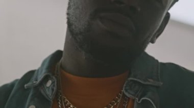 Siyahi adamın boynundaki zincirlerle dışarıda kameraya rap yaparken orta boy yakın çekimi.