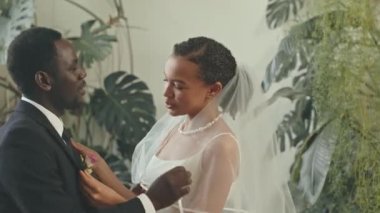 İyi giyimli, genç, Afro-Amerikan çiftin düğün töreninden önce birbirlerine yakın durup konuştukları belden yukarısını çek.