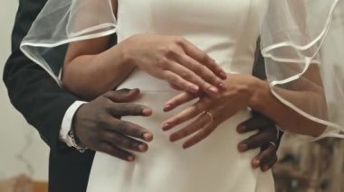 Tanımlanamayan çok ırklı yeni evli çiftin düğün sonrası romantik fotoğraf çekimi sırasında el ele tutuşması.